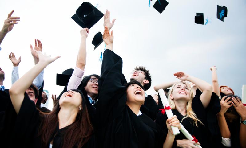Graduates throwing graduation caps into the air