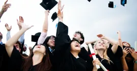 Graduates throwing graduation caps into the air