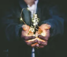 holding lightbulb in open hands to represent values