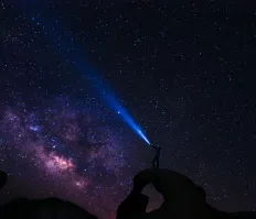 Person holding a flashlight in galaxy