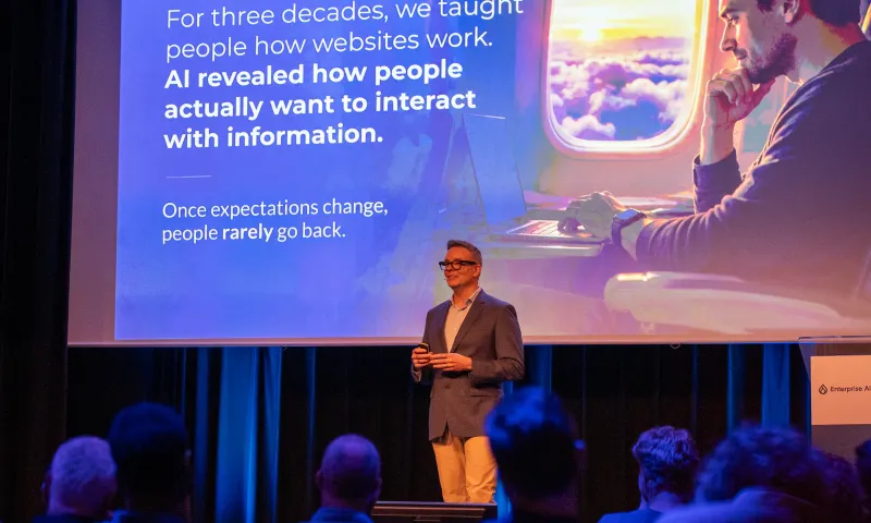 Gleen presenting on stage to a seated audience, with a slide explaining how AI is changing the way people interact with information.