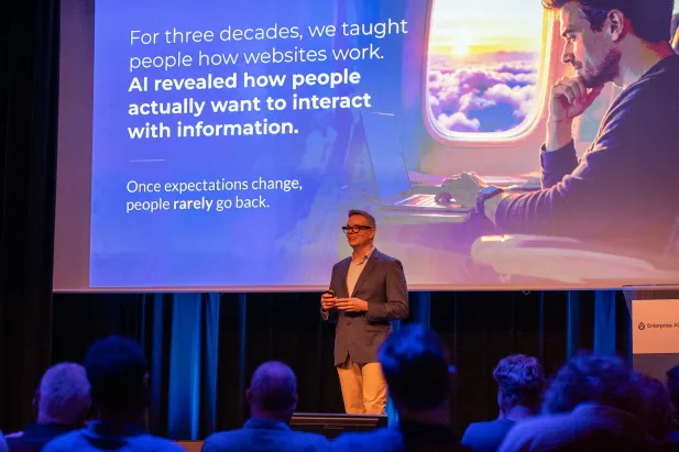 Gleen presenting on stage to a seated audience, with a slide explaining how AI is changing the way people interact with information.
