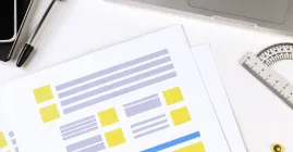 Website forms on a print out next to a laptop