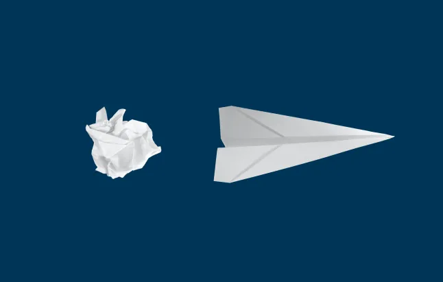 Crumpled paper ball next to paper airplane