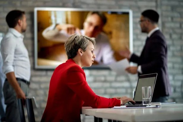 Woman working on laptop with video call in the background