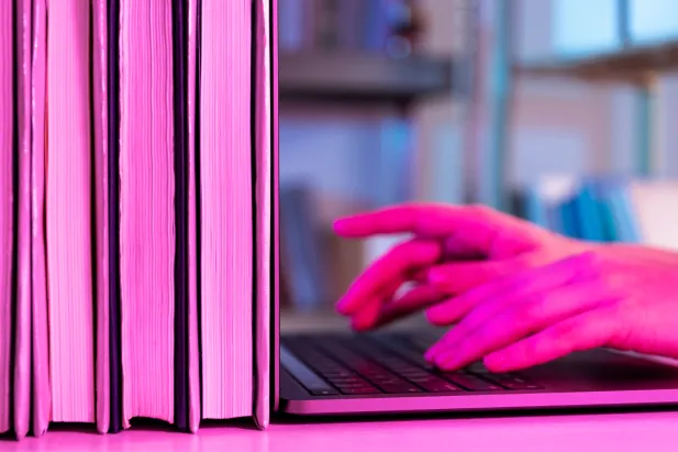 Person typing on laptop in a library
