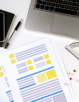 Website forms on a print out next to a laptop