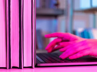 Person typing on laptop in a library