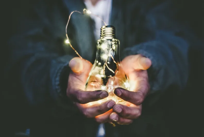 holding lightbulb in open hands to represent values