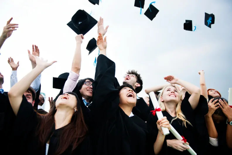 Graduates throwing graduation caps into the air