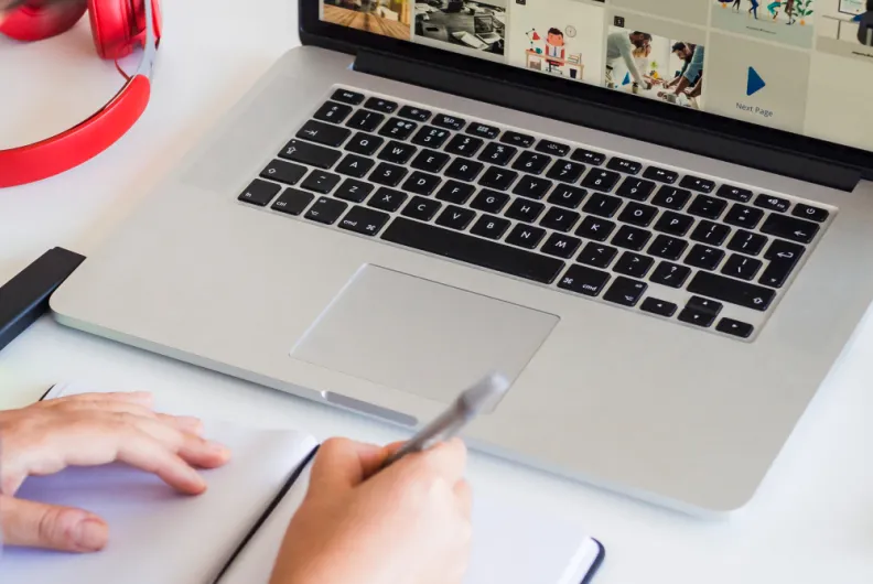 Person taking notes by a laptop